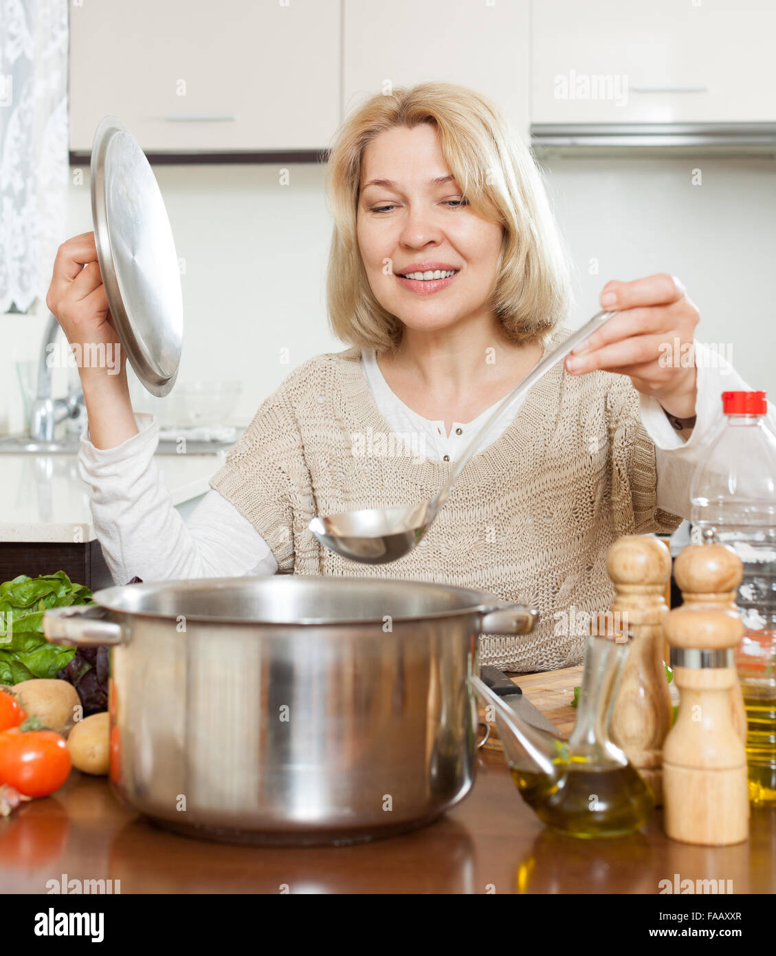 smiling mature woman cooking soup in